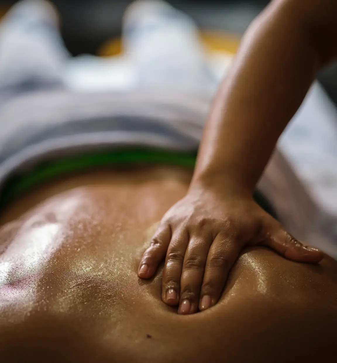 Eine entspannende Massage in einem Wellnesshotel, bei der eine Hand sanft über den Rücken gleitet, ideal für Erholung und Wellness.