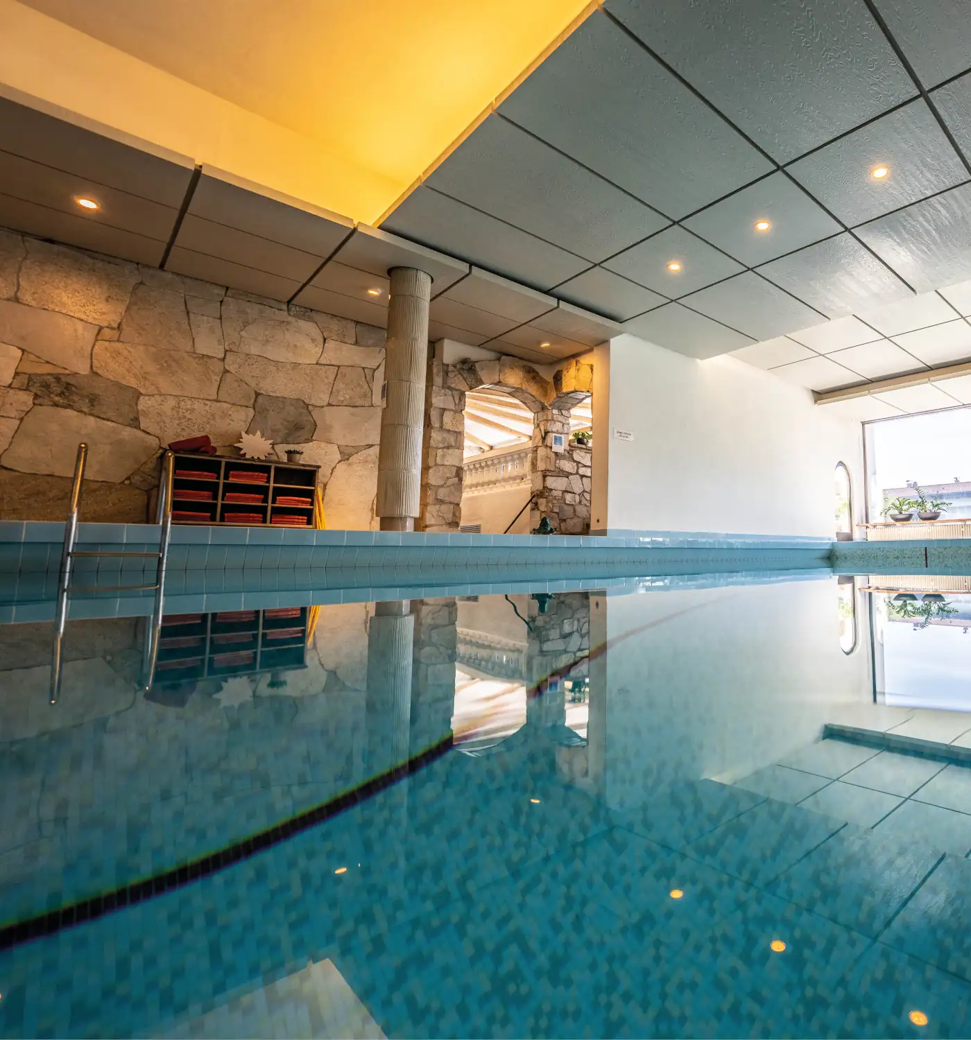Der Innenpool im Hotel Alpenblick, in einem Wellnessbereich mit eleganter Beleuchtung und steinernen Wänden, bietet pure Erholung.
